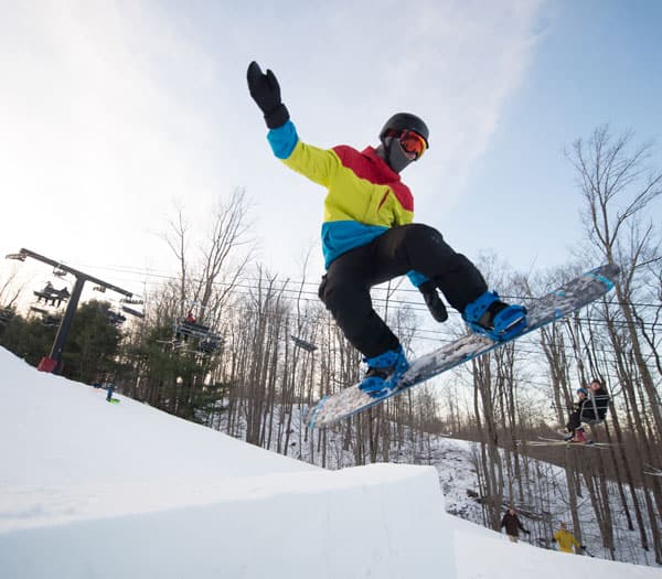 Man on snowboard jumping off of snow ramp