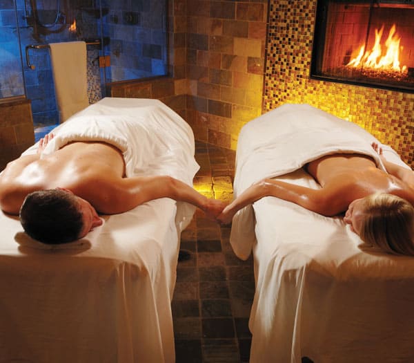 Couple at spa getting massages next to fireplace