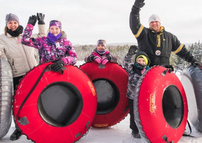 Family waving with snow tubes