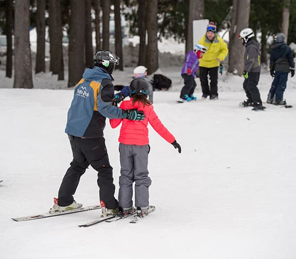 Child getting instructed by guy on skis