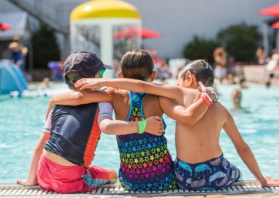 Three kids hugging by the pool