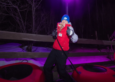 woman giving thumbs up while pulling a snow tube during lunar lights snow tubing