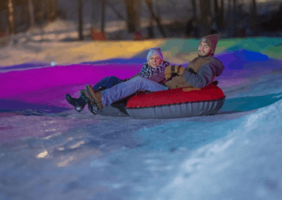adults riding on snow tubes during lunar lights snow tubing