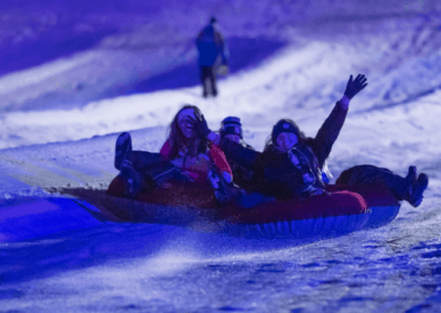 girls on snow tube hill with lights for lunar lights snow tubing