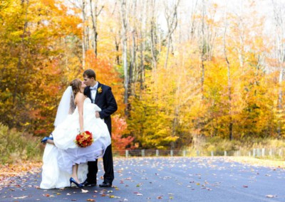 married couple kissing on the side of a road in the woods at peek n peak resort