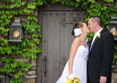 married couple kissing in front of a door with vines
